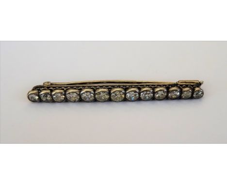 A diamond brooch, mounted with a row of thirteen cushion shaped diamonds, graduating in size to the centre stone, length 5.7c