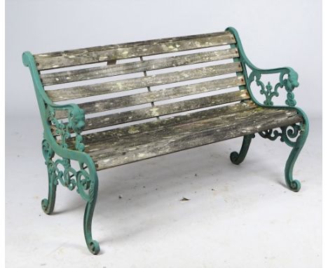 A 20th century green painted cast iron garden bench, with lion mask arm terminals and scroll supports united by wooden slats,