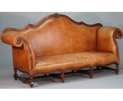 An 18th century Italian style tan leatherette upholstered sofa, with shaped back and frieze and scroll arms on stained beech 