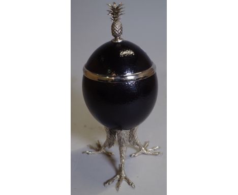 A black painted ostrich egg converted into a lidded trinket pot, with white metal mounts and claw feet, 29cm high. 