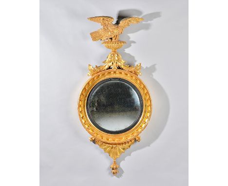 A William IV gilt framed convex mirror with eagle crest and star burst lower frieze, the ball mounted frame with ebonised sli