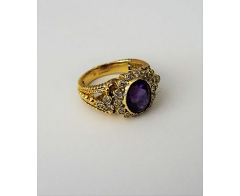 A gold, amethyst and diamond set oval cluster ring, mounted with the oval cut amethyst at the centre, in a surround of circul