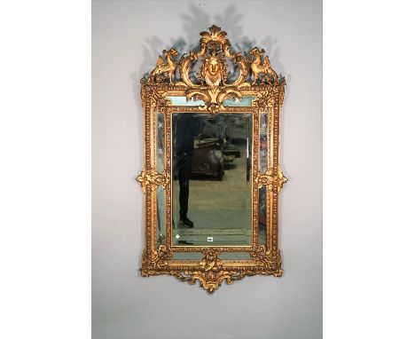 An 18th century style Italian mirror the opposing 'C' scroll crest centred by a female face mask, flanked by griffins over a 