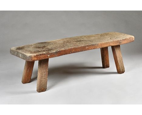 A 19th century pig bench, the rectangular elm slab top on four stake supports, 145cm wide x 43cm high. Illustrated 