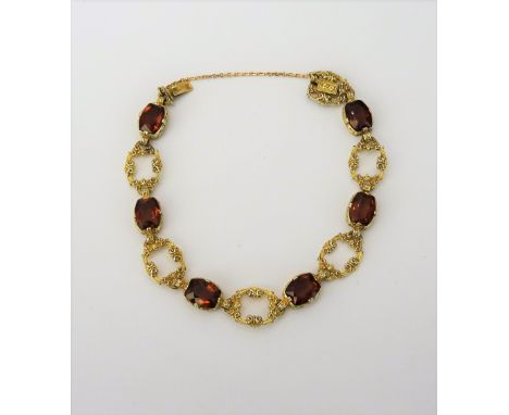 A gold and citrine set bracelet, designed as a row of oval openwork links alternating with cushion shaped citrines, detailed 