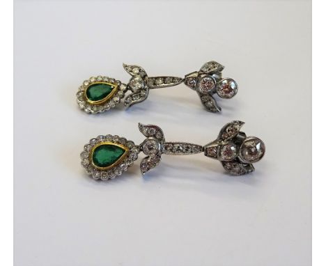 A pair of diamond and emerald pendant earrings, each with an associated drop, collet set with a pear shaped emerald at the ce