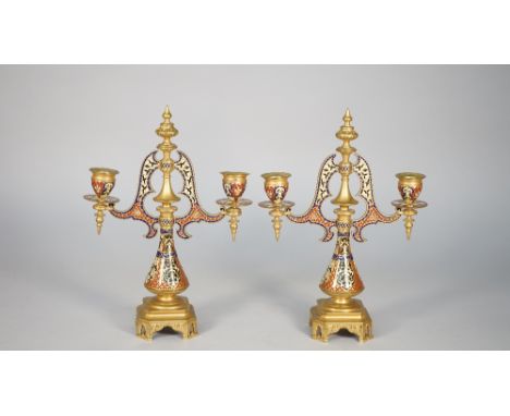 A pair of French champlevé brass twin branch candelabra, late 19th century, of Gothic architectural form, 30cm high, (2). Ill