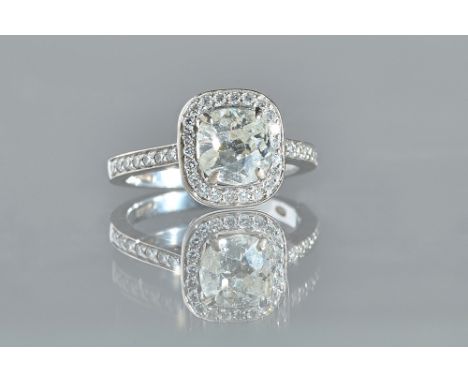 A 18ct White gold and diamond single stone ring, the cushion cut diamond four claw set in circular cut diamond surround and d