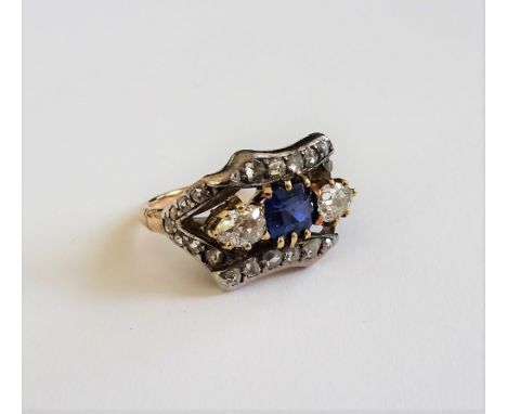 A gold and silver set, sapphire and diamond ring, claw set with the cushion cut sapphire to the centre, between two pear shap