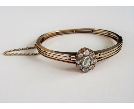 A diamond set hinged bangle, circa late 19th Century, set with a diamond cluster, the central oval rose cut diamond approxima