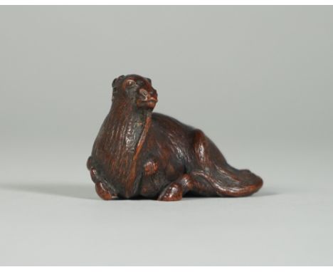 A Japanese wood netsuke of a recumbent goat, Edo period, 19th century, signed, (a,f), 4.25cm. length. 