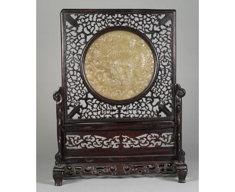 A Chinese wooden table screen with inset bowenite panel, late 19th/early 20th century, the circular panel carved with a coile