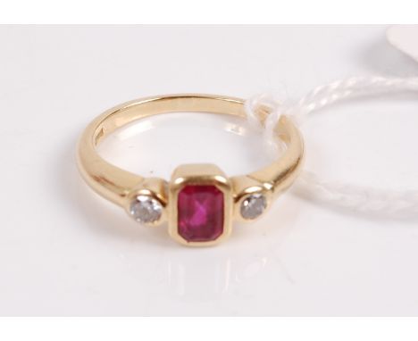 A 18ct gold ruby and diamond ring, the centre emerald cut ruby measuring approx 5.5x3.75mm, flanked to either side with singl
