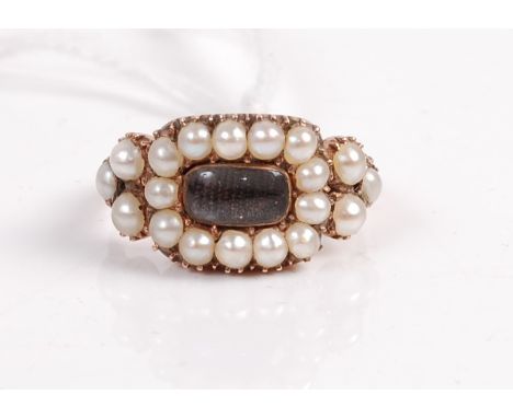 A Victorian yellow metal seed pearl set mourning ring, having crystal glass concealing finely plaited hair, within a surround