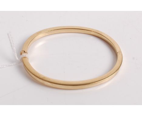 A yellow metal hollowed square section hinged bangle, stamped 9kt and tested as 9ct, 12.6g, dia.7cm