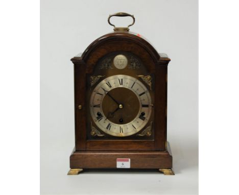 A modern mahogany cased bracket clock having an arched brass dial with silvered chapter ring, Roman numerals and chiming move