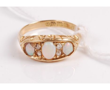 A vintage 18ct gold opal and diamond ring arranged as three cabochon opals each dispersed with two diamond highlights, 3.2g, 