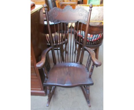 An oak stick back rocking chair with a solid seat on ring turned legs and rocker base