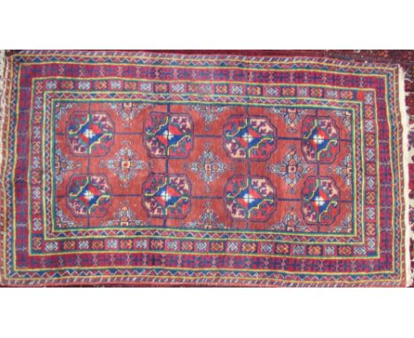 A Turkoman rug with a light red ground and eight geometric medallions and multi coloured guard stripes, 89 x 161cm