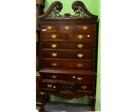 A reproduction Chippendale style hardwood chest on stand, with scrolled pediment above eight drawers, the base with four smal
