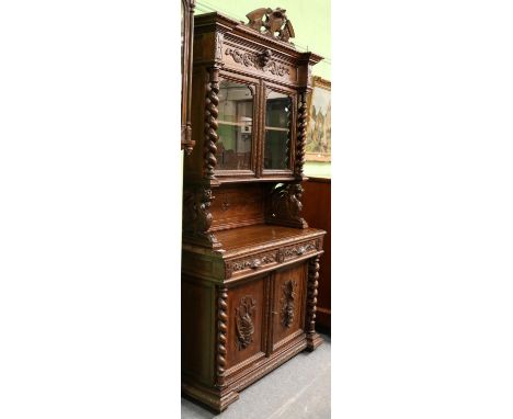 A Victorian carved oak cabinet,the glazed upper section above a recess, over two drawers and two cupboard doors 