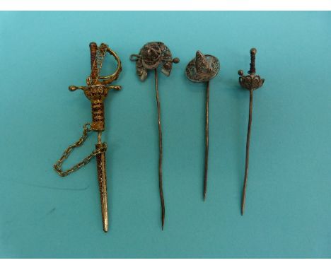 Three white metal filigree stick pins, one in the form of a horseshoe, jockey cap and crop, one a sword and the other a hat, 