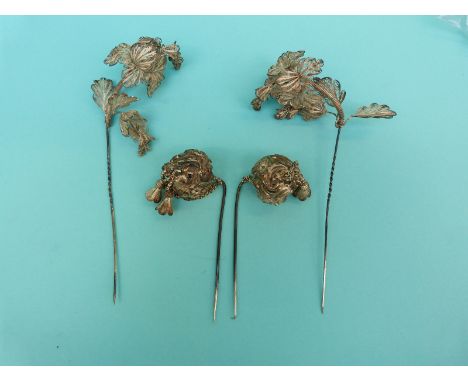 A pair of white metal filigree stick pins in the form of flowers with spring sections and a pair of white metal continental s