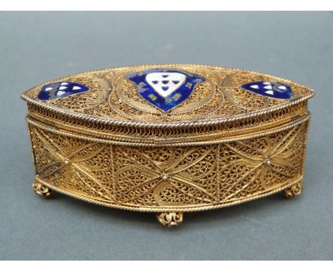 A Portuguese white metal gilt filigree lidded pot with blue and white enamel armorial design and silver marks to edge, length