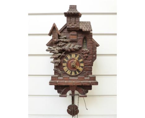 Early to mid twentieth century Black Forest carved cuckoo clock in the style of an alpine building, the pendulum bob in the f