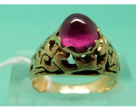 A yellow metal ring set with a ruby cabochon with pierced shoulders (Size I)