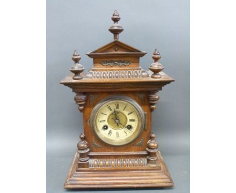 A c1900 German walnut-cased mantel clock with ornate carved finials and Roman dial