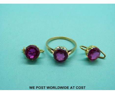 A yellow metal ring set with a round cut synthetic ruby with matching earrings. 