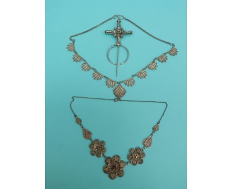 A white metal filigree necklace made up of three layered flowers, a filigree necklace made up of foliate sections and a filig