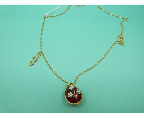A yellow metal pendant in the form of a guilloche enamel egg set with clear paste on an 9ct gold chain, 10.3g. 