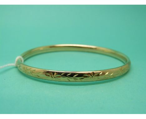 A 9ct gold bangle with floral decoration, weight 5.9g 