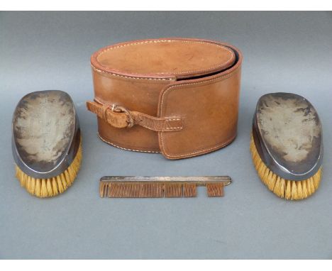 A leather cased George V hallmarked silver gentleman's travelling set comprising two brushes and comb, all Birmingham 1911 ma