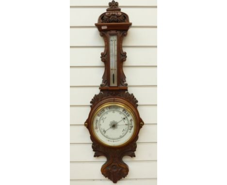 Aneroid wall barometer c1910 with carved oak surround, thermometer incorporated above, 20cm dial