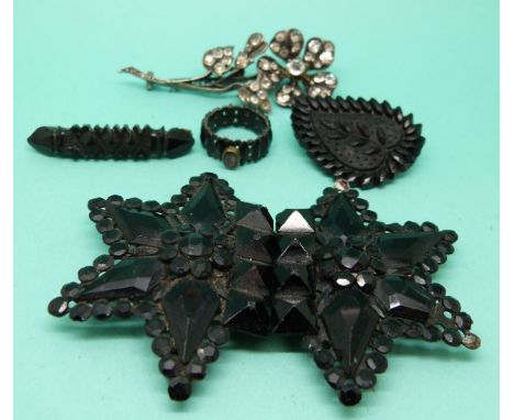 A jet buckle, two Victorian jet brooches, a jet ring set with a pink stone and an early white metal brooch set with paste 