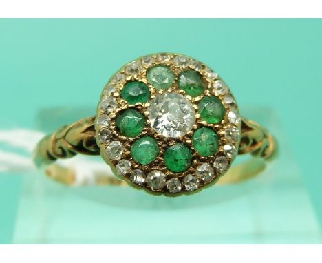 An 18ct gold Victorian ring set with a diamond surrounded by emeralds and a further row of diamonds (Size R)