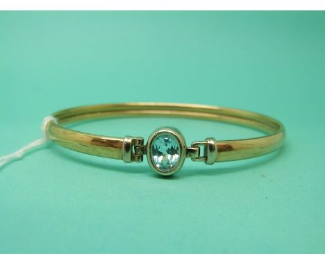 A 9ct gold bangle set with a blue topaz, 7.4g. 