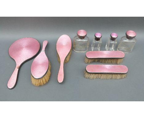 A hallmarked silver and guilloche enamel dressing table set comprising hand mirror, three various brushes and two dressing ta