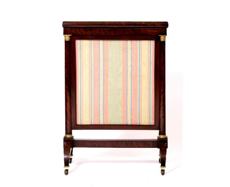 AN EMPIRE MAHOGANY AND GILT MOUNTED FIRE SCREEN with curved legs terminating in brass casters, 63cm x 89cm x 36cm