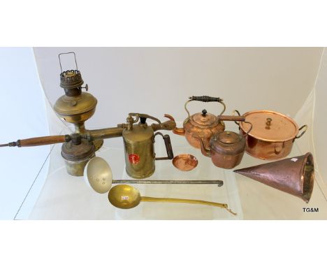 A collection of brass and copper items to include vintage plant sprayer, beer warming jug, oil lamp and copper kettles