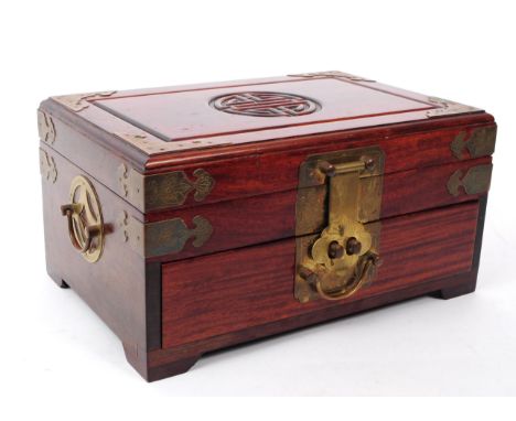 A vintage 20th century Chinese hardwood jewellery box / chest. Having brass mounts, carved centre motif. With etched brass mo