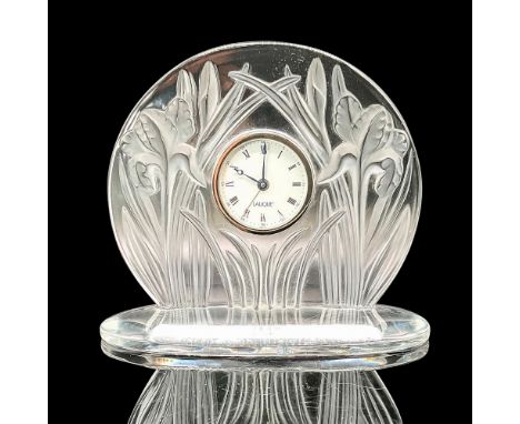 The clock showcases sculpted tall iris flowers on each side in frosted glass, complemented by a clear crystal body, resulting