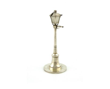 A French novelty silver table cigar lighter, retailed by Cartier, Paris, modelled as a street gas lamp, on a spread circular 