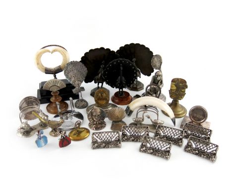 A large collection of menu card holders, comprising silver examples: a silver-mounted boar tusk holder, Edinburgh 1906, easel
