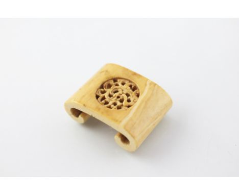 A Chinese carved ivory brush or pen rest, of scroll form and with central pierced Mon carved with a dragon, 5.7cm wide 