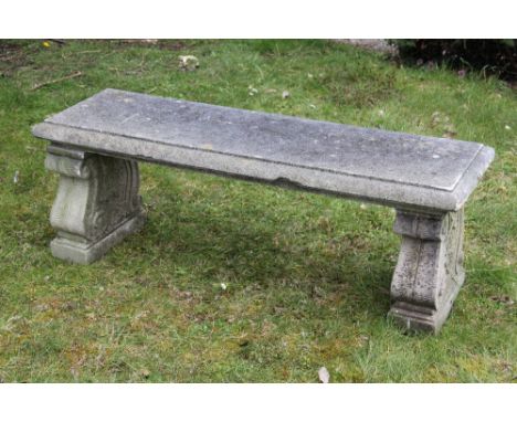 A reconstituted stone garden bench, on scroll block supports, 46cm H x 131cm W