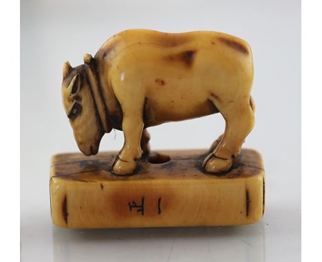 A 19th century Japanese carved ivory netsuke of a bison, on rectangular base, signed, 3.75cm